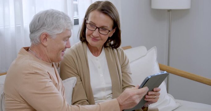 Senior woman holds tablet while retired husband looks, gestures, and smiles as couple choose painting references before creative activity at home, encouraging bonding, relaxation, and mental wellness.