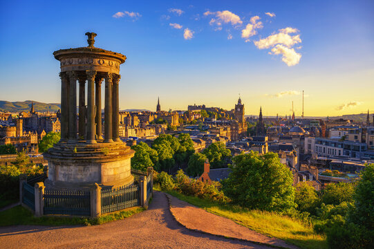 Golden sunset view from Calton Hill with Dugald Stewart Monument overlooking the historic Edinburgh skyline in Scotland.