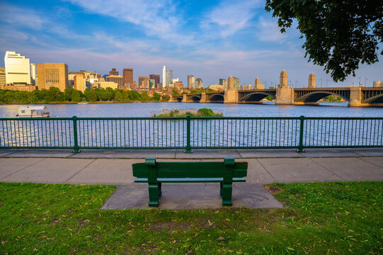 Empty park bench overlooking the Charles River with view of Longfellow Bridge and downtown Boston skyline in Massachusetts, USA