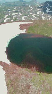Vertical Drone Shot of Volcanic Crater Lake surrounded by Red Soil, Green Slopes, and Melting Snow