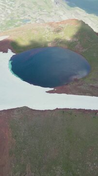 Vertical Video of Scenic Volcanic Crater Pond with Turquoise Water and Patchy Snow