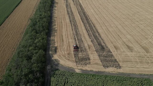 Drone aerial view of tractor working on harvested wheat field