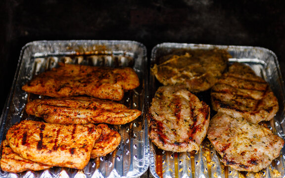 Putensteaks und Schweinenackensteaks werden auf Holzkohlebriketts gegrillt.