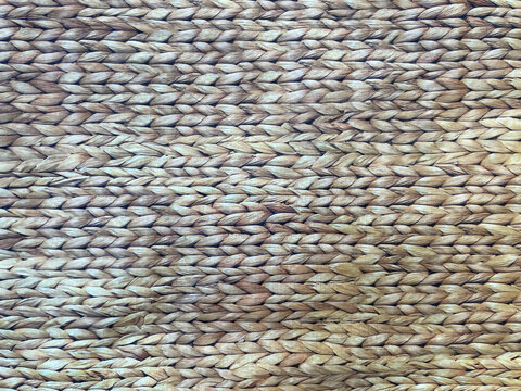 Natural woven straw texture with braided fibers in warm beige and brown tones. Rustic handcrafted pattern creates an organic background ideal for interior design, crafts and branding.