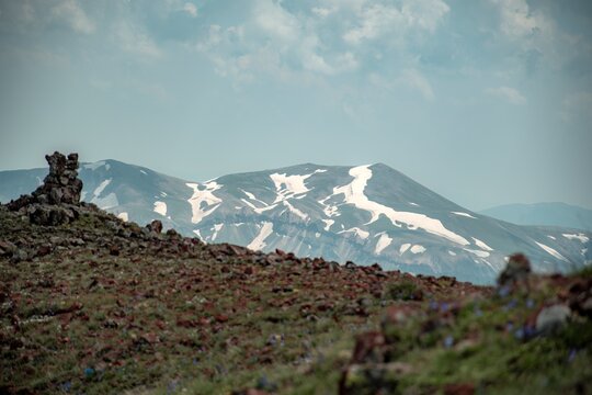 Panoramic Landscape of Volcanic Plateau with Red Earth Cone, Patchy Snow, and Fluffy Cumulus Clouds