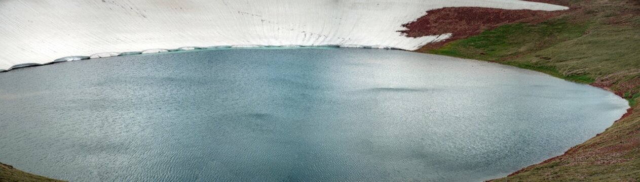 Aerial View of Alpine Crater Lake Edge with Emerald Water Transitioning to Deep Blue Deep