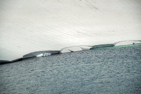 Aerial View of Alpine Crater Lake Edge with Emerald Water Transitioning to Deep Blue Deep