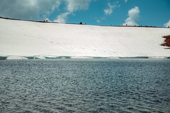 Aerial View of Alpine Crater Lake Edge with Emerald Water Transitioning to Deep Blue Deep