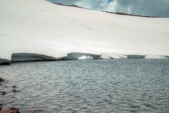Aerial View of Alpine Crater Lake Edge with Emerald Water Transitioning to Deep Blue Deep