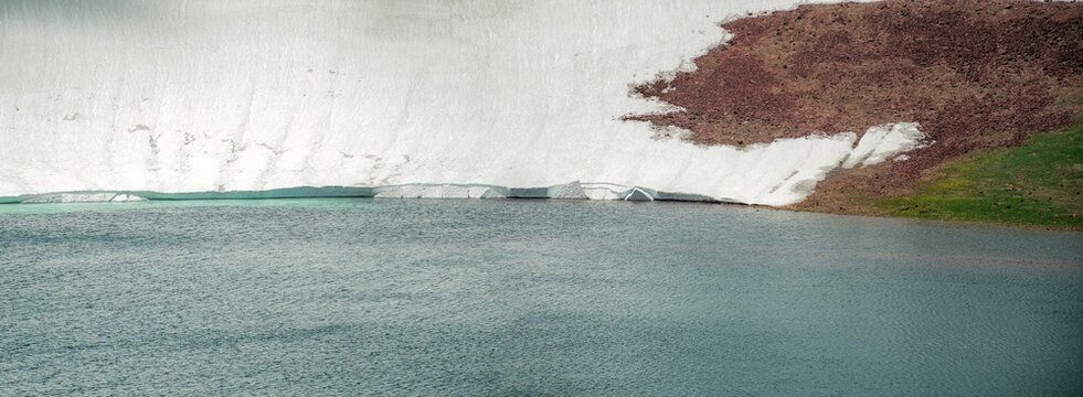 Aerial View of Alpine Crater Lake Edge with Emerald Water Transitioning to Deep Blue Deep