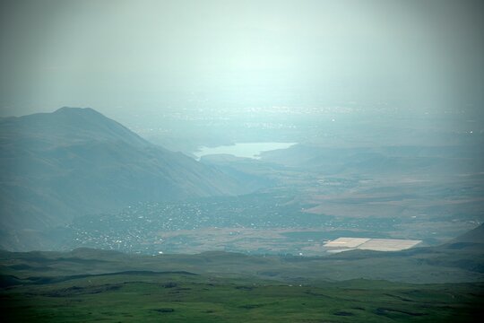 Panoramic Landscape of Volcanic Plateau with Red Earth Cone, Patchy Snow, and Fluffy Cumulus Clouds