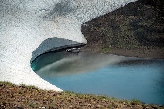 Aerial View of Alpine Crater Lake Edge with Emerald Water Transitioning to Deep Blue Deep