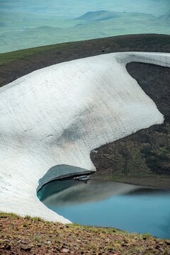 Aerial View of Alpine Crater Lake Edge with Emerald Water Transitioning to Deep Blue Deep