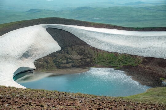 Aerial View of Alpine Crater Lake Edge with Emerald Water Transitioning to Deep Blue Deep