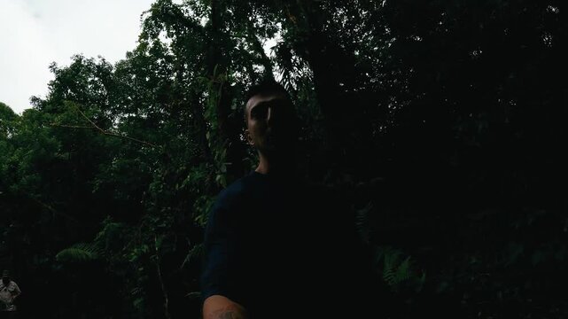 Young male vlogger with a camera recording a selfie video while walking on a path in the dense jungle of Arenal Volcano National Park in Costa Rica