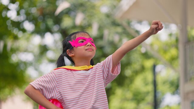 Happy Asian little kids pretending to be superheroes playing together outdoors in park. Children roleplay, imaginative fantasy, and brave hero childhood lifestyle concept.