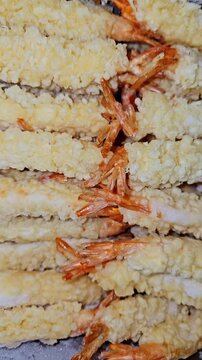 A close-up view of fresh, crispy shrimp tempura neatly arranged in rows, showing golden breading and shrimp tails.