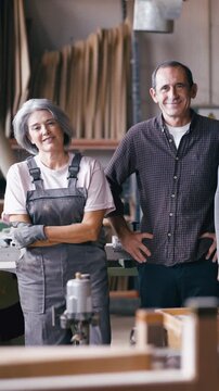 Experienced senior craftspeople posing together in their carpentry workshop. A man and a woman proud of their family business and handicraft