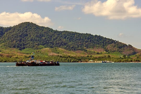 Modern passenger transport vessel navigating open ocean waters in Southeast Asia. Coastal scenery of Krabi province visible in the background with visible water wake. 