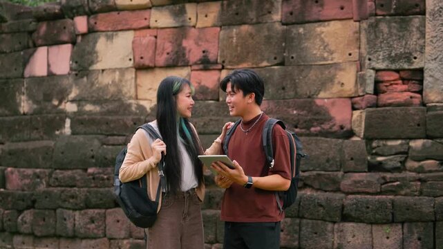 Asian tourist couple at ancient Khmer stone ruins looking at map