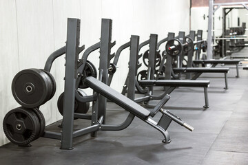 Fototapeta premium Row of bench press stations with plates in gym