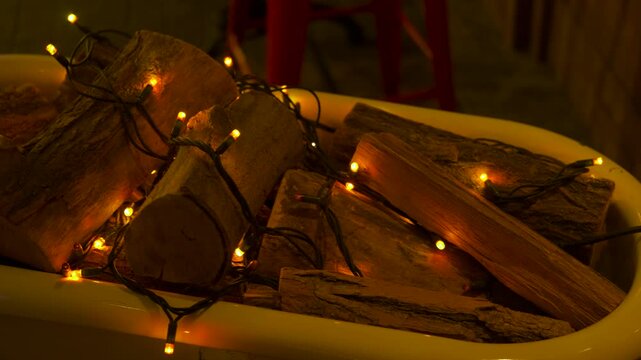 Bathtub filled with firewood and warm lights decoration. Bathtub filled with firewood and decorated with a string of warm yellow christmas lights, creating a cozy design element for a warm