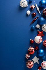 Fototapeta premium Festive red and blue Christmas ornaments and baubles arranged on a navy vertical background for holidays