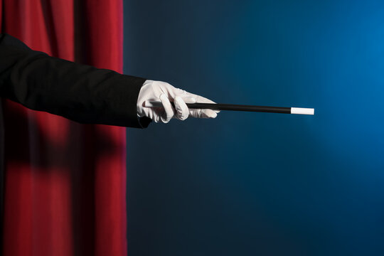 Magician showing trick with wand on stage, closeup