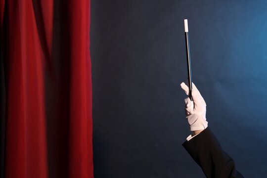 Magician showing trick with wand on stage, closeup