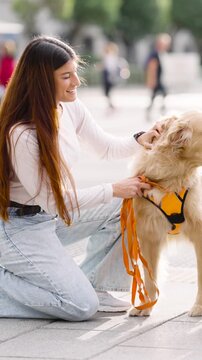 Young woman affectionately petting her beautiful golden retriever on a city sidewalk. Happy canine companion enjoying the attention from its owner