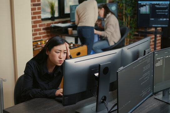 Asian Programmer Reacting to Compiling Error at a software development desk, showing coding error, system failure and algorithm debugging during programming work.