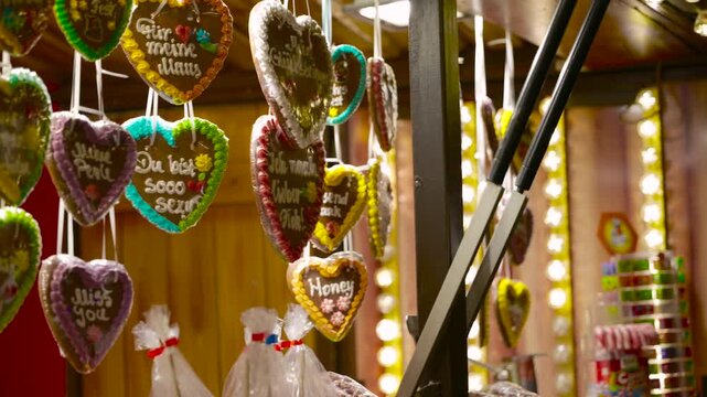 Hanging gingerbread hearts at a traditional german christmas market. Colorful lebkuchenherzen, traditional german gingerbread hearts, hanging at a festive christmas market stall decorated with warm