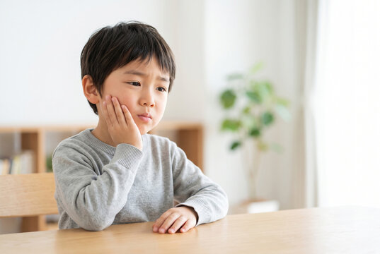 頬を押さえて歯痛を我慢する男の子 Generative AI