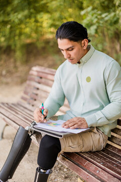 Latino man with prosthetic legs working in park