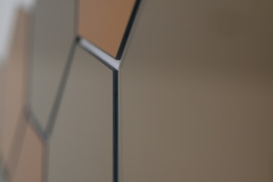 Contemporary hexagonal mirror wall panels with bronze and champagne finishes. Elegant geometric home d&eacute;cor displayed on a white wall with a modern minimalist style.