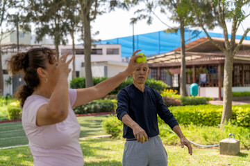 Obraz premium Older adults training coordination with tennis balls outdoors