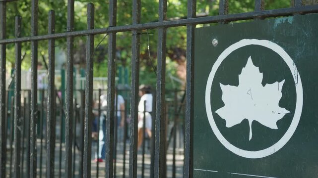 oblique leaf logo on fence outside swings in public park in Brooklyn