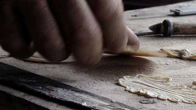 Bell Maker Hand Lifting Decorative Wax Saint Medallion from Workbench - 4K