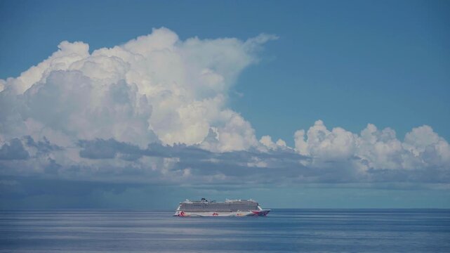 Norwegian Cruise, Caribbean Sea - APRIL 21, 2026:Colorful cruise ship with distinctive hull artwork glides peacefully across calm deep blue waters under dramatic billowing cumulus clouds in serene sky