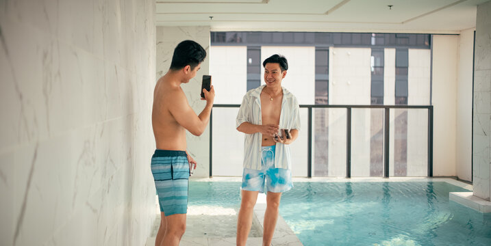 Gay couple enjoying poolside leisure, taking pictures, and sharing happy moments