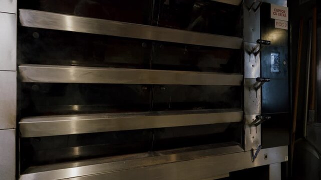 Industrial bakery oven with visible steam and metal shelves, showcasing the interior design and functionality of commercial baking equipment in a professional kitchen setting