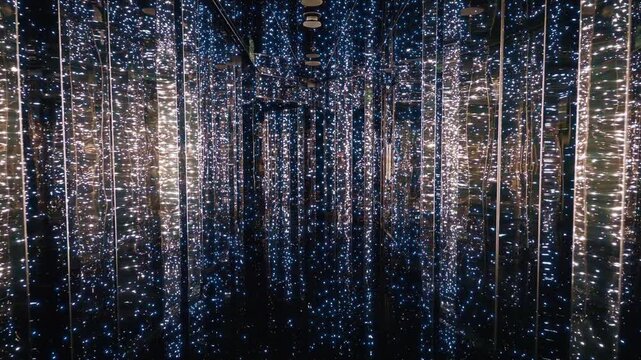 Mesmerizing infinity mirror room featuring thousands of blue and warm white LED lights cascading from ceiling to floor.