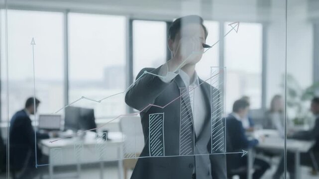 Medium shot of a professional pointing to a property insurance fund graph on a glass board with blurred office coworkers in the background.