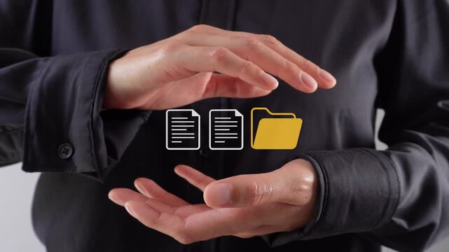Close-up of hands gesturing over digital icons. Hands show protection or handling of files. Ideal for tech, business, or data management themes