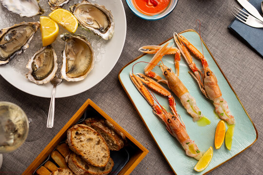 Raw oysters on crushed ice and whole raw langoustines on rectangular plate at elegant restaurant