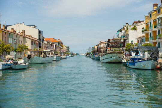 Mandracchio fishing canal in Grado with moored fishing boats and colorful waterfront buildings in summer