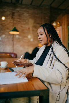 Pensive woman professional flipped book page working on tablet, female entrepreneur using digital stylus for project research at cafe, nomadic lifestyle and remote education concept, indoor.