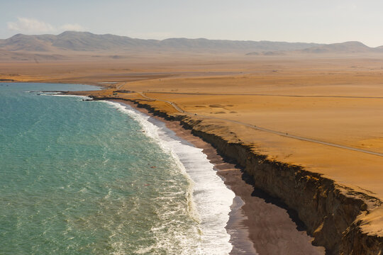 Turquoise Pacific Ocean waves meeting the rugged desert coastline of Paracas National Reserve in Peru