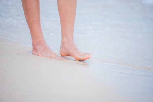 Woman walking barefoot summer beach. Close up legs walk along wave of sea water sand beach. Enjoy freedom barefoot leg walk outdoor. Relaxation Travel woman foot walking tropical summer beach