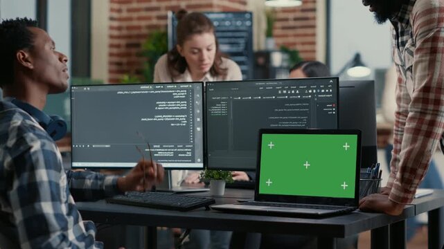 Software developer works at a desk with chroma key screen replacement, combining algorithm development, software testing and mockup presentation, while handling code diagnostics.